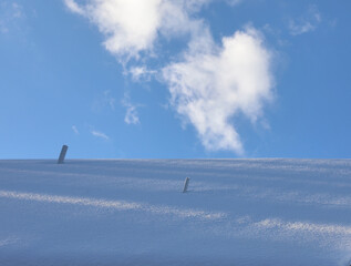 Background with snowy roof and blue sky with white clouds.