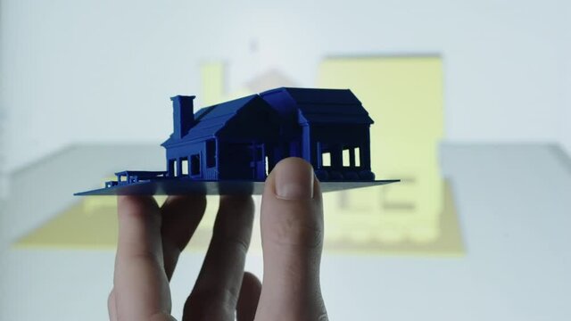 Close up of 3d Printed blue mini house with construction plan on pc in background shot in 4k