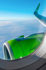 Beautiful view from the airplane window in sunny clear weather. Wing and turbine of an airplane on a background of blue sky.