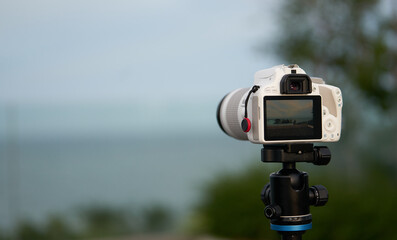 white camera on stand on blur beach front view