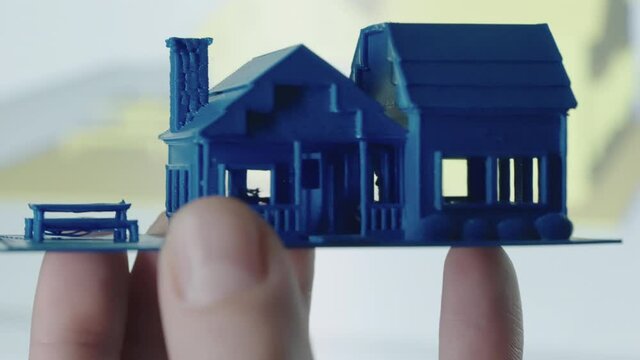 Close up of 3d Printed blue mini house with construction plan on pc in background shot in 4k