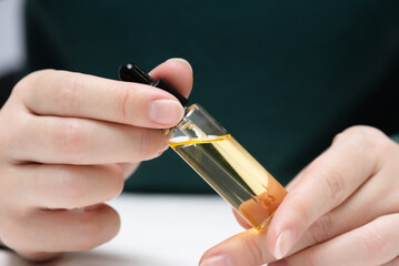 Cuticle oil bottle in the female hands close up. Finger nail care.