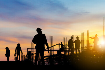 Silhouette of Engineer and worker on building site, construction site at sunset in evening time.