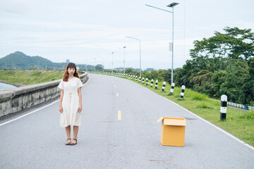 Young asian thai woman hipster curly hairstyle on white dress standing on the road with empty cardboard box.