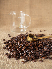 Coffee beans with gold measuring spoon and measuring cup on linen texture background