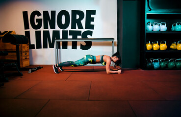 Young woman in the gym doing plank exercise 