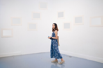 Young asian thai woman in blue dress in white art gallery.