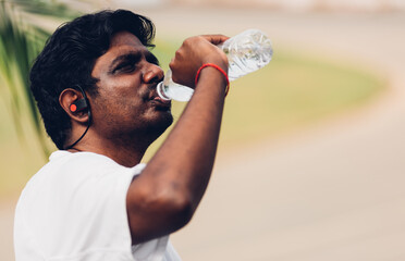 Close up Asian young sport runner black man wear athlete headphones he drinking water from a bottle...