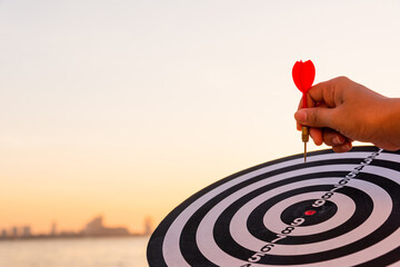 Hand hold of dart arrow on bullseye (bull's-eye) dartboard is the target of purpose challenge...