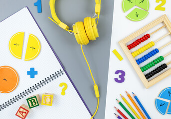 Creative trendy colors ABC, numbers, shapes, earphones, notepad, pencils, fractions on gray background. Interesting funny preschool games . Education, back to school concept.  Flat lay, top view	