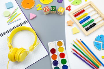 Creative trendy colors ABC, numbers, shapes, earphones, notepad, pencils, fractions on gray background. Interesting funny preschool games . Education, back to school concept.  Flat lay, top view	