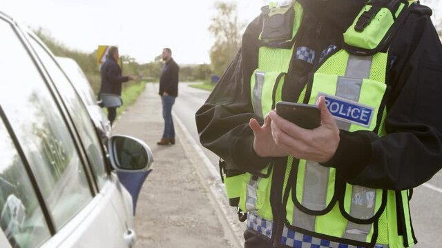 Close up of female traffic police officer taking down details of traffic accident on mobile phone at scene of road traffic accident - shot in slow motion