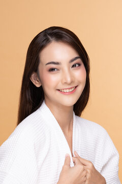 Beautiful Asian woman wearing bathrobe smile with clean and fresh skin Happiness and cheerful with positive emotional,isolated on Beige background,Beauty Cosmetics and spa Treatment Concept