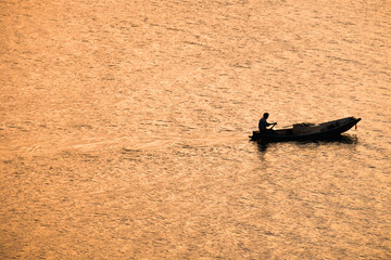 Shadows of the fishermen paddle back to the shore in the evening when the sun's rays reflect the glittering surface.