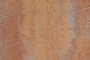 Horizontal close-up image of a cracked stucco wall painted in southwestern style colors, a useful image for copy space.