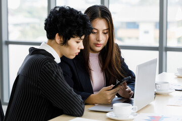 Two diversity businesswoman working together at desk in office.
