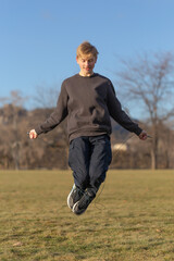 Teenager working out outdoors, having fun, exercising and jumping with a skipping rope.
