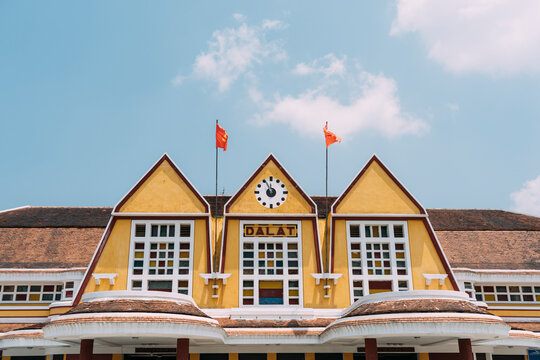 Old train station sign with clock and flags in Dalat, Vietnam.