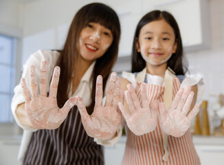 A cute and beautiful Asian mother and lovely 7 years show hands that dirty and stain with flour...