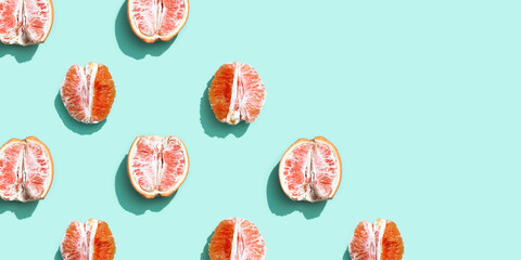 Pattern with red without peel orange or grapefruit on bright turquoise. Minimal summer fruits concept.