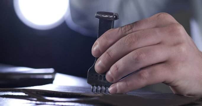 Skin Processing Wizard Prepares Leather for Edge Stitching. Tanner Sets up Leather Cutter and Strikes with Hammer. Piercing Holes. Close-up. Manual Labor. Work at Home. Small Business. Self-employed
