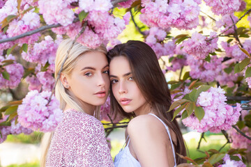Fototapeta premium Spring girls fashion. Beautiful young woman enjoying flowering garden. Girlfriends couple.