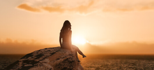 a girl sits on rock sunset.