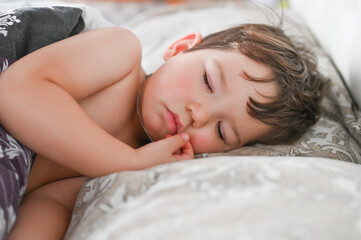 Obraz na płótnie Canvas Close up portrait of little boy sleeping in bed. Happy bedtime concept