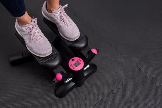 Woman doing exercise on stepper machine. Close-up photography of foots with copy space for text.