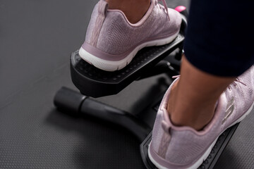 Rear view of woman's foots wearing sports shoes using stepper.