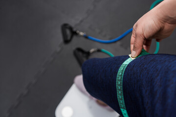Close up leg checking volume with measuring tape on a black background with sports elements.