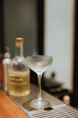 A frozen empty coupe glass on the bar counter. Lifestyle vertical image. Selective focus.