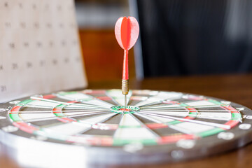 Fototapeta premium The dart board has an arrow thrown into the center of the shooting target for business targeting.