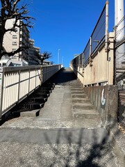 looking  up to an old stairway to a bridge over railway in Shibuya, Tokyo, Japan on a sunny day blue sky