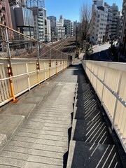 looking down to a stairway to a bridge over railway in Shibuya, Tokyo, Japan on a sunny day blue sky