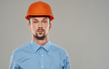 Male architect in orange paint and in a blue shirt on a gray background portrait