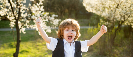 Obraz premium Happy child at school backyard. Blooming garden. Spring boy at park.