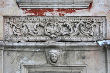 Elements of the architectural decor of the building. A fragment of the wall of an old stone house with peeling plaster.