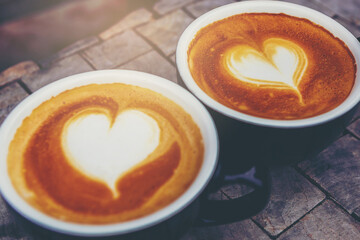 Double cups of cappuccino with heart shape latte art on top. Lovely coffee concept.