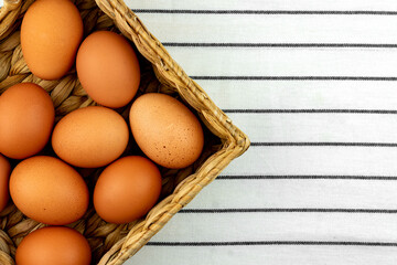 Zero waste easter background. No plastic concept. Minimal style. Beige water hyacinth box with brown chicken eggs on textile background.