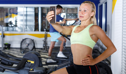 Fototapeta na wymiar Female athlete taking selfie during training in fitness center