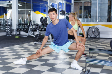 Positive fitness couple warming up during indoors stretching workout