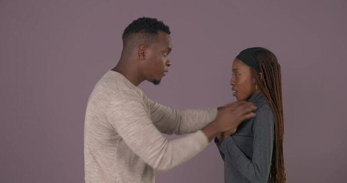 Side view portrait of African couple in quarrel. Angry man yelling and blaming his scared girlfriend and shaking her. Physical and psychological violence. Domestic abuse