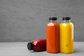 Three plastic bottles with freshly squeezed juice on gray background