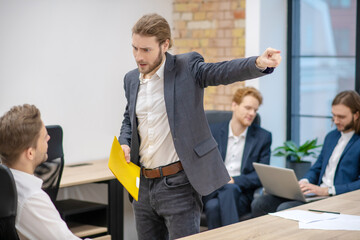Angry man with folder gesturing away