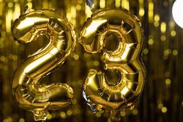 Golden number 23 twenty three made from an inflatable balloon, on a yellow background. One of the...