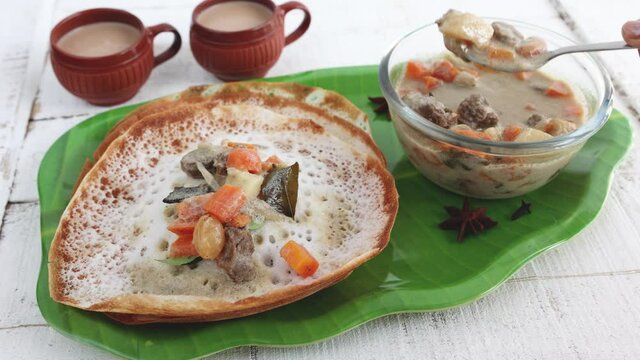Appam, Hoppers and mutton stew Kerala breakfast food and Indian milk tea chai, christian breakfast India Sri Lanka Tamil Nadu 4K slow motion video footage fermented rice pan cake. Indian veg food.