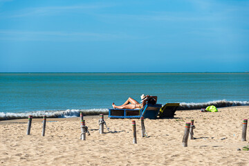 Girl tanning under a bright sun on a beach
