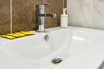 Fototapeta premium White ceramic sink with liquid soap bottle and packets with disposable shampoo