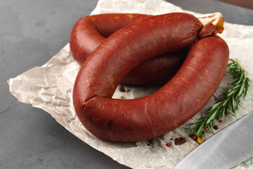 Meat sausage on parchment on gray background